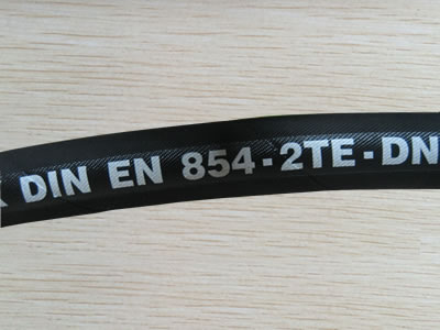 A section of EN854-2TE hydraulic hose is on the table.