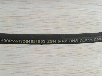 A section of SAE 100 R2 AT hydraulic hose is on the table.